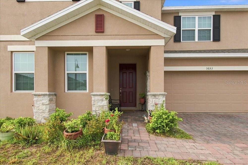 The exterior of a two-story house features a covered entryway, a stone-accented porch, and a garage — 5653 CAMILLA STREET, ST CLOUD, FL