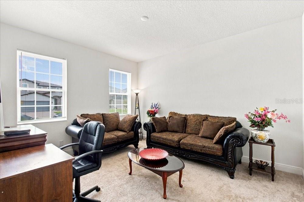 A living room features two dark brown sofas, a coffee table, and a desk — 5653 CAMILLA STREET, ST CLOUD, FL
