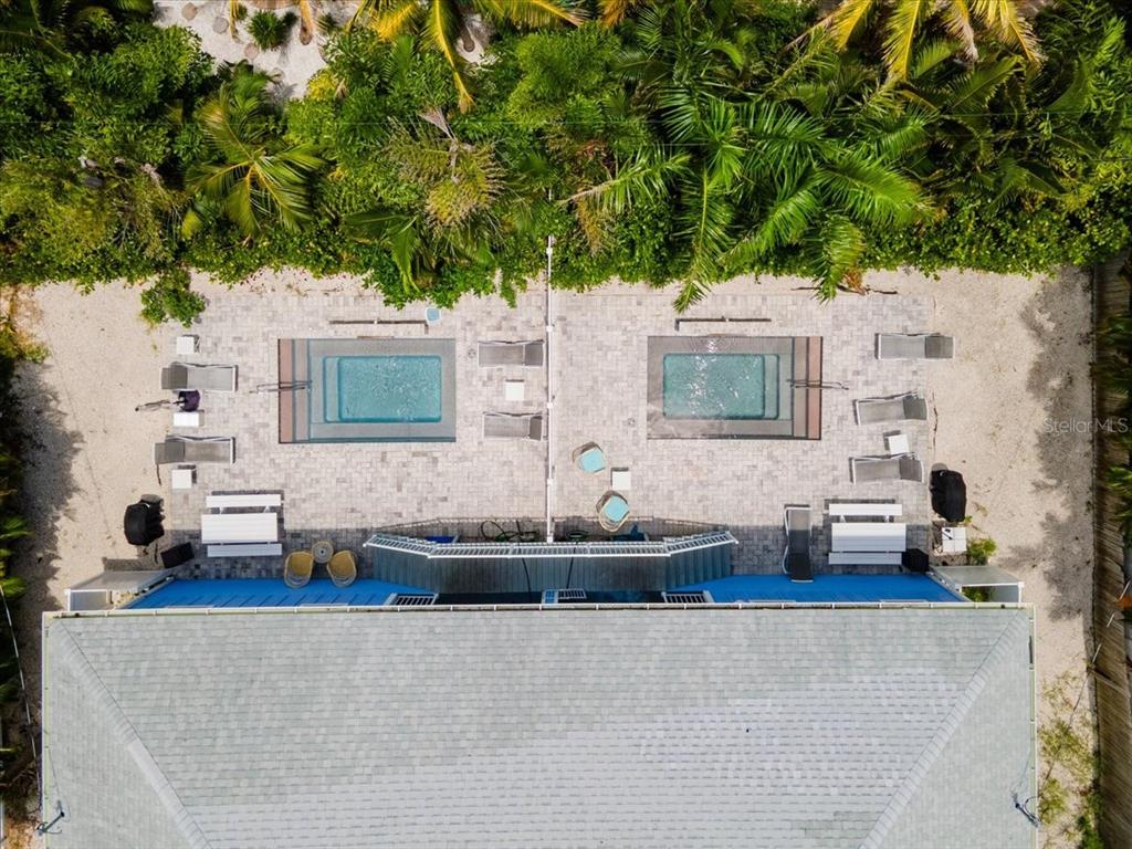 An aerial view shows a house with two side-by-side pools and lounge chairs on pavers — 308 57TH STREET UNIT A & B, BRADENTON BEACH, FL