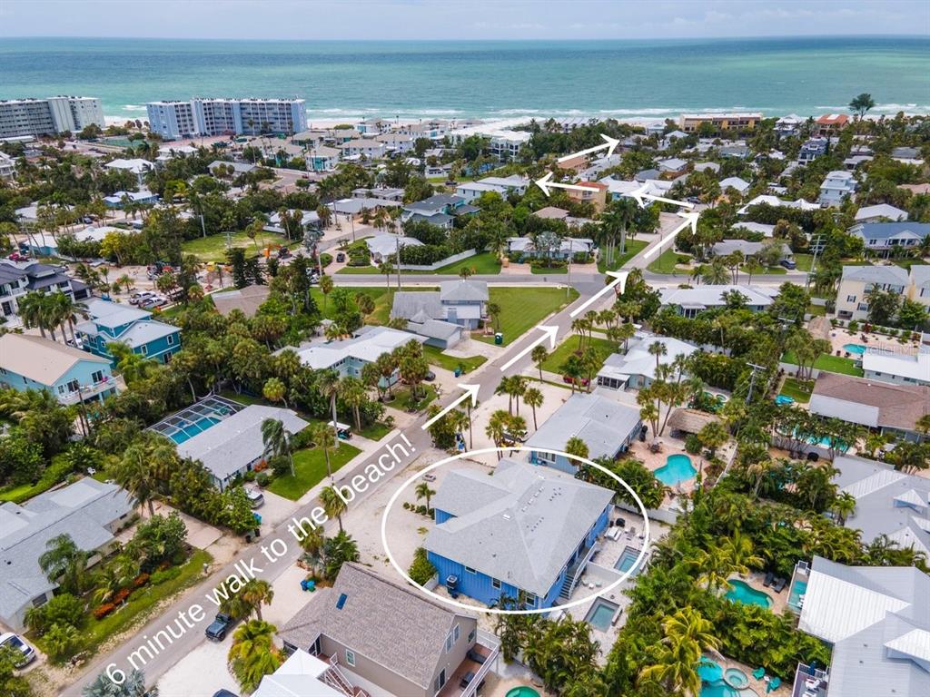 An aerial view shows a blue house with a pool near a beach and road — 308 57TH STREET UNIT A & B, BRADENTON BEACH, FL