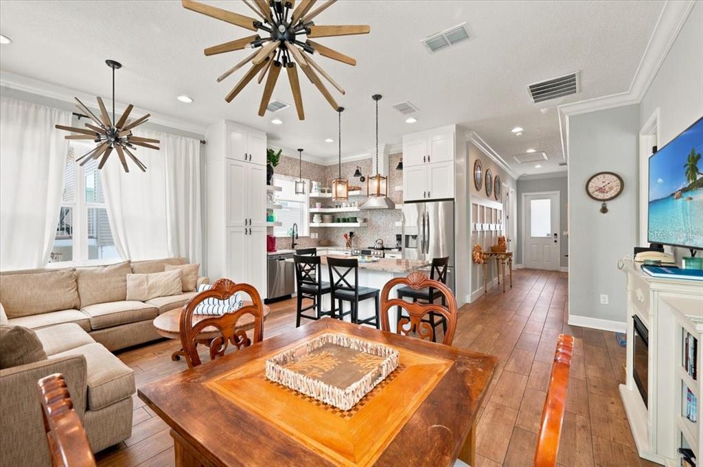 An open-concept kitchen and living area features wood flooring, white cabinetry, and two starburst chandeliers — 308 57TH STREET UNIT A & B, BRADENTON BEACH, FL