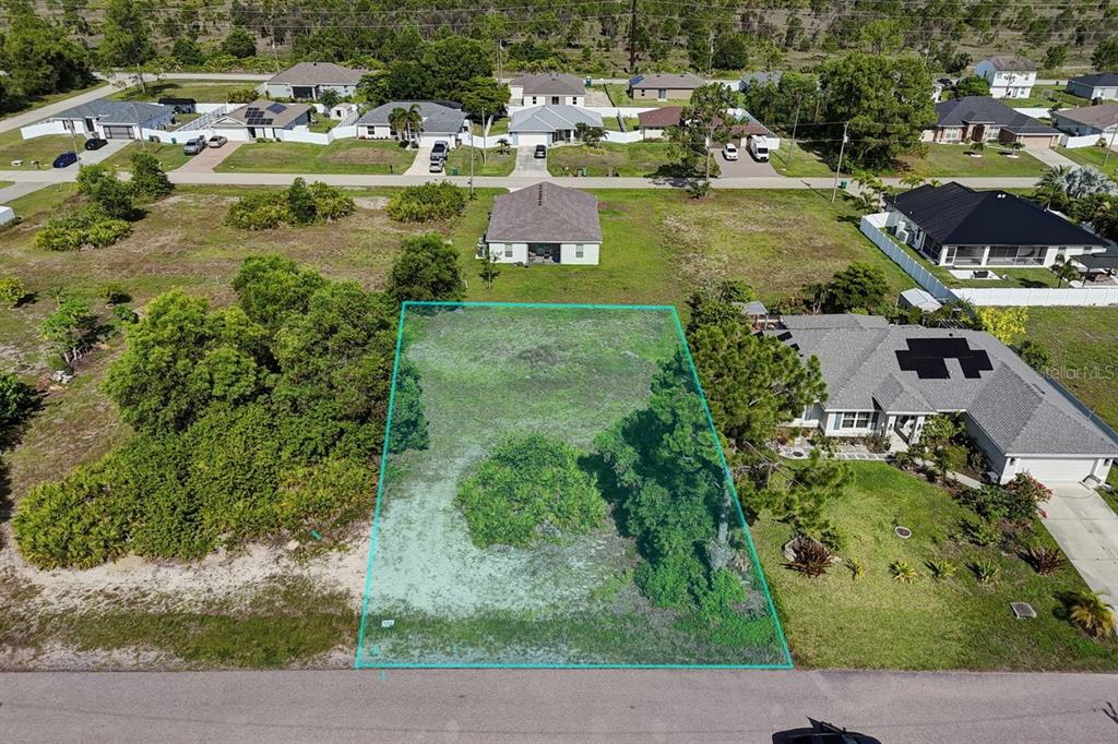 An aerial view shows a vacant residential lot outlined in blue between two houses — 3912 NE 9TH AVENUE, CAPE CORAL, FL