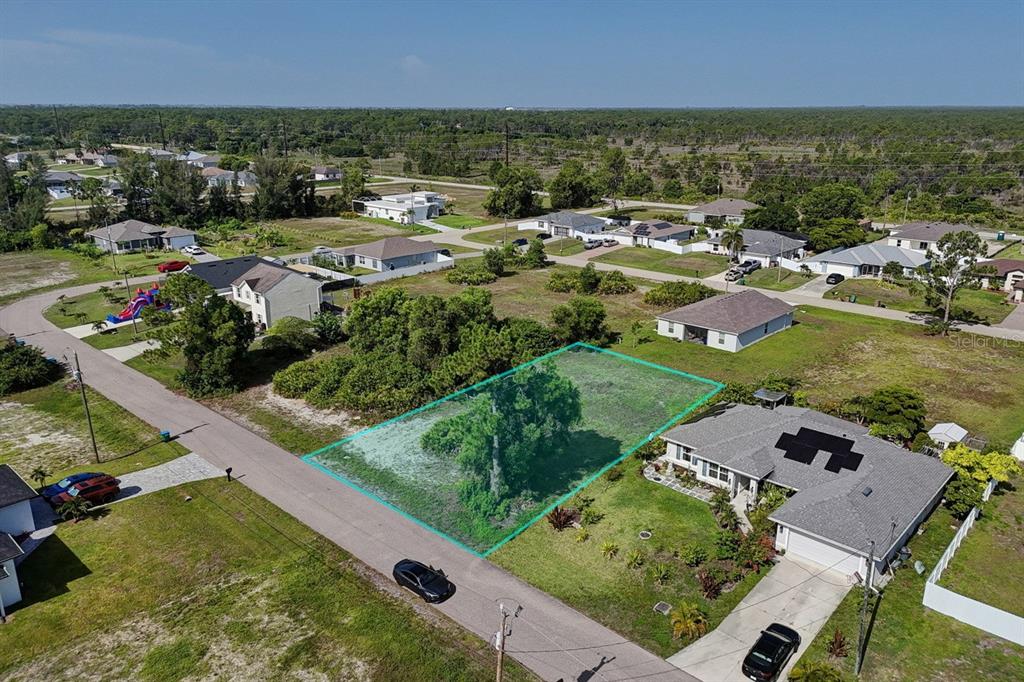 An aerial view shows a vacant, rectangular residential lot outlined in teal between two houses — 3912 NE 9TH AVENUE, CAPE CORAL, FL