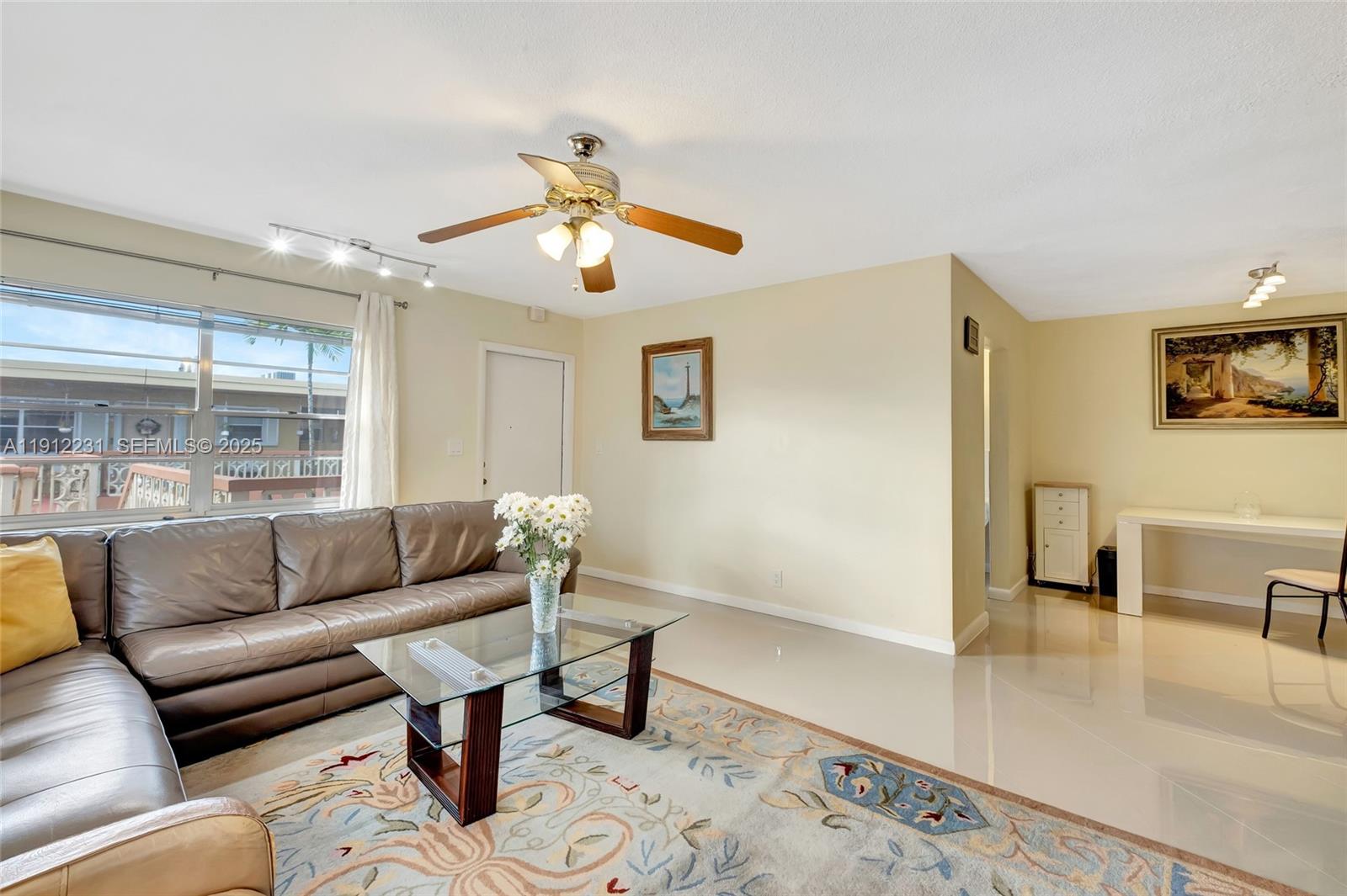 A living room features a leather sectional, glass coffee table, area rug, and dining area — 1943 Monroe St # 310D, Hollywood FL 33020, HOLLYWOOD, FL