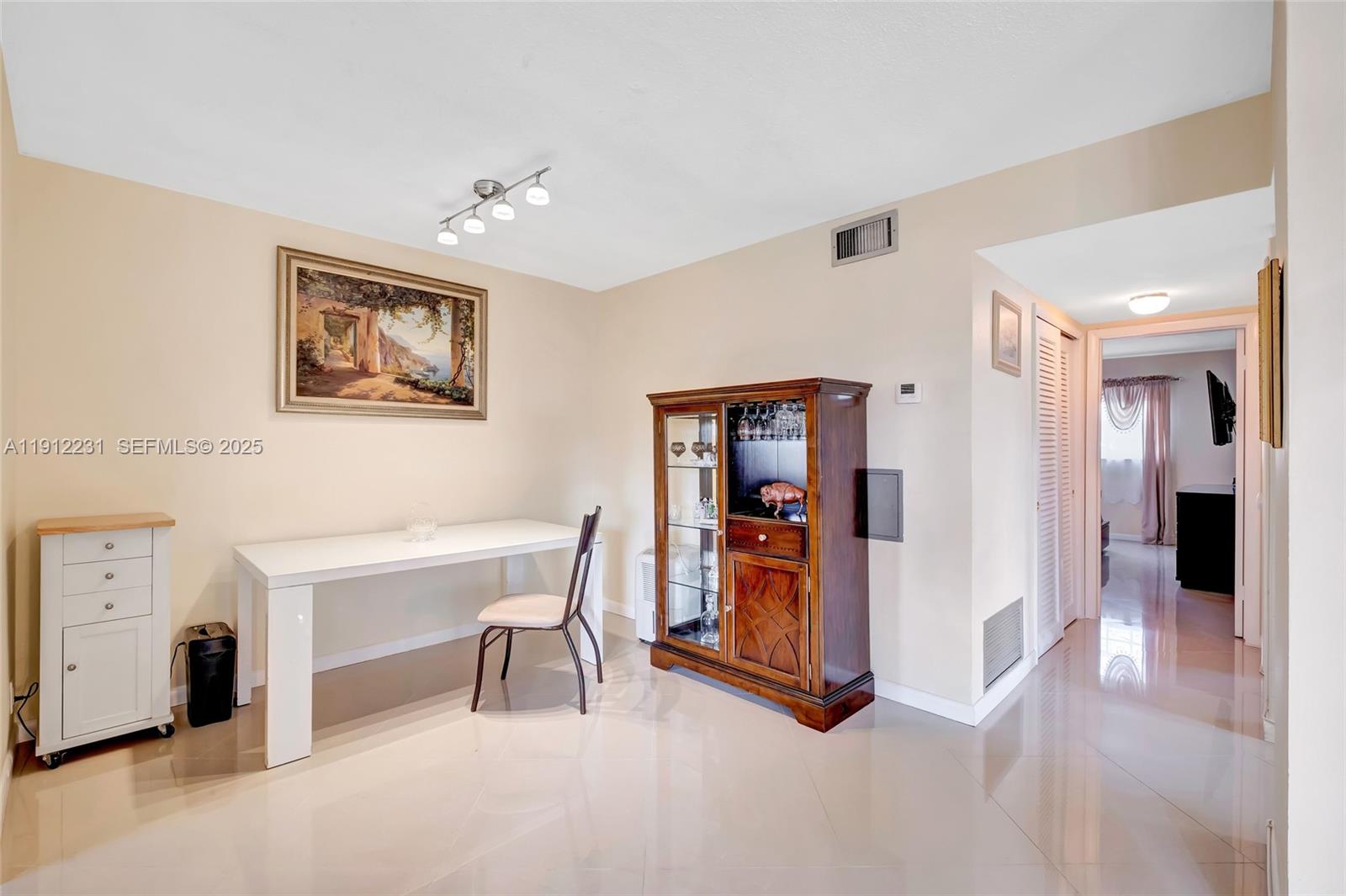 A dining area features a white table, a wooden hutch, and tile flooring — 1943 Monroe St # 310D, Hollywood FL 33020, HOLLYWOOD, FL