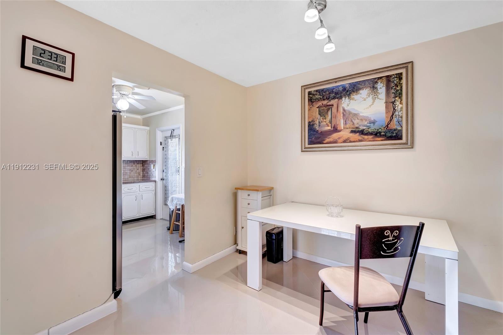 A dining area features a white table, a single chair, and a framed landscape painting — 1943 Monroe St # 310D, Hollywood FL 33020, HOLLYWOOD, FL