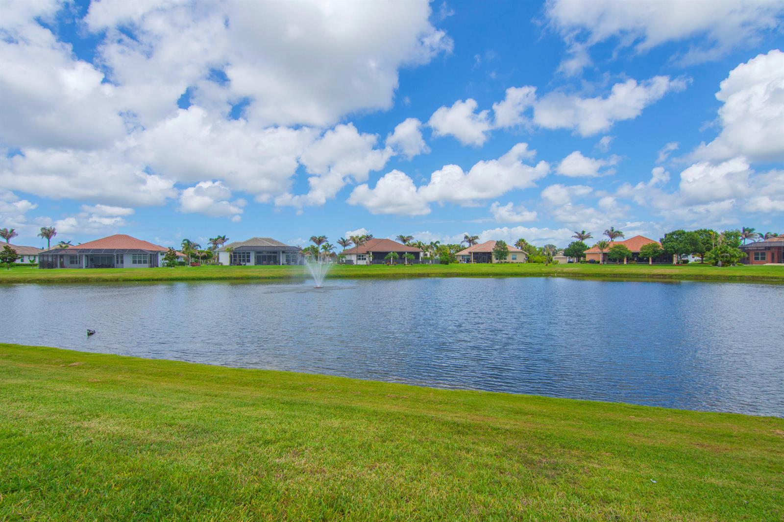 A pond with a fountain sits in front of several houses under a cloudy sky — 470 Pittman Avenue, Vero Beach FL 32968, VERO BEACH, FL