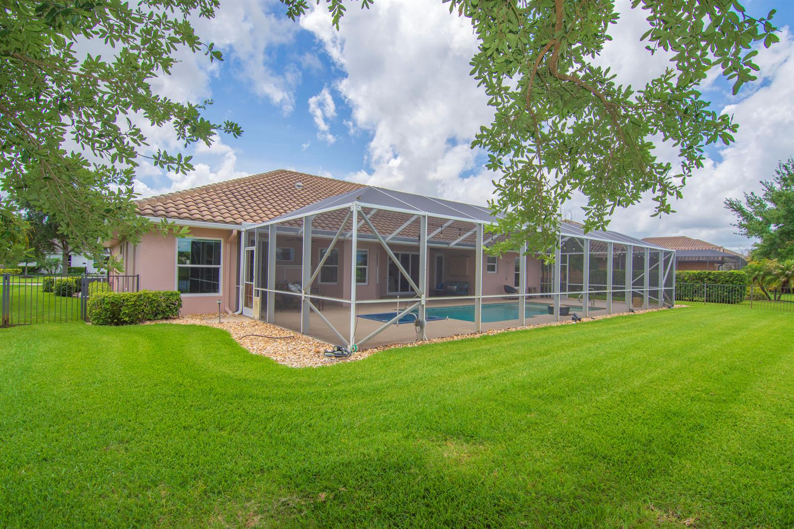 A rear view of a house featuring a screened-in pool enclosure and a grassy yard — 470 Pittman Avenue, Vero Beach FL 32968, VERO BEACH, FL