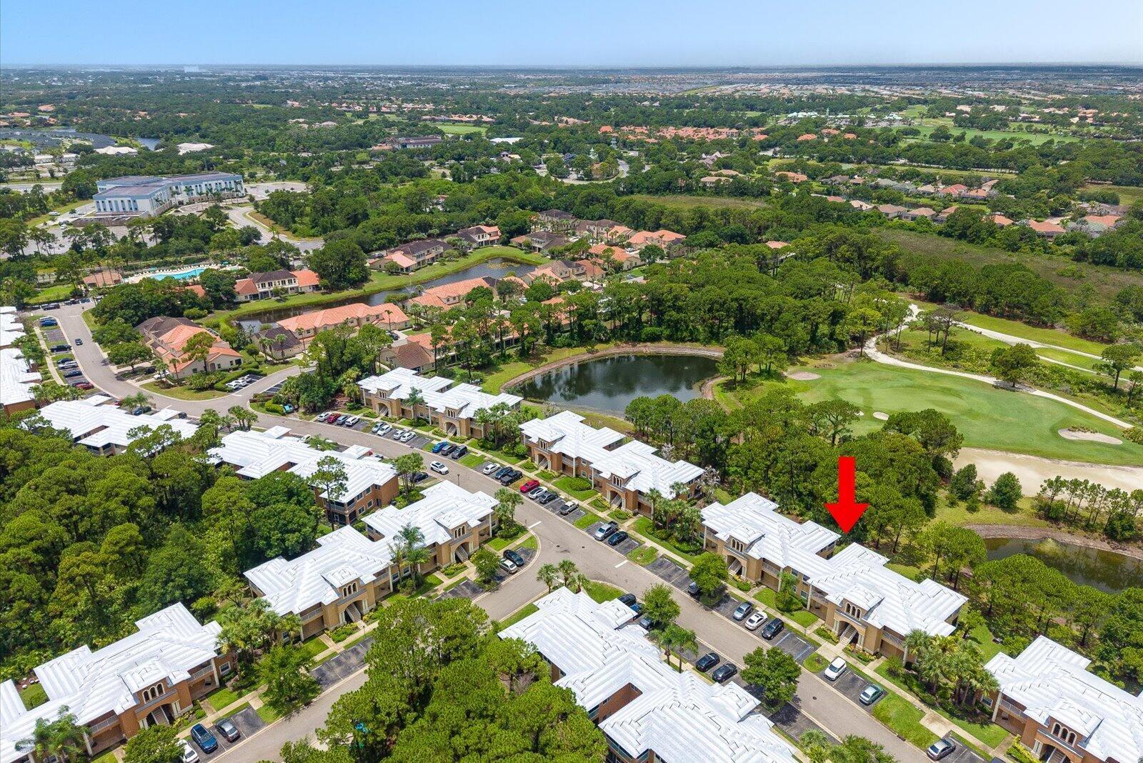 An aerial view shows a multi-unit residential complex surrounded by trees, a pond, and golf — 8340 Mulligan Circle # 2024, FL 34986, FL