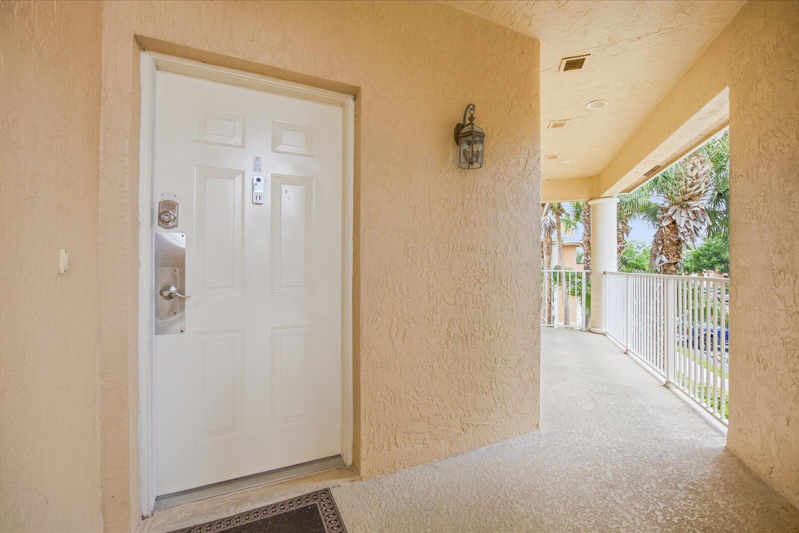 A white front door with a keypad lock opens onto a covered outdoor balcony — 8340 Mulligan Circle # 2024, FL 34986, FL