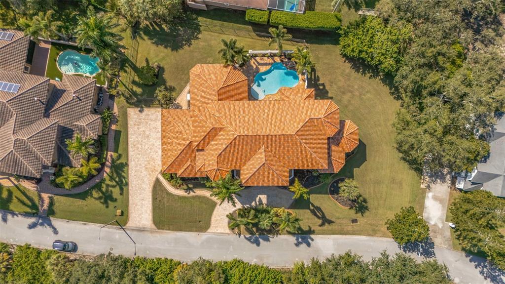 An aerial view shows a large house with a tiled roof, pool, and paved driveway — 1079 ASHLAND AVENUE, TARPON SPRINGS, FL