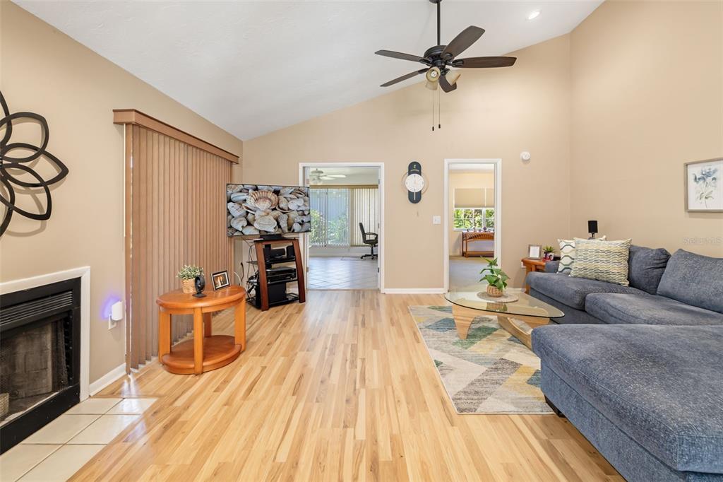 A living room with light wood flooring, a fireplace, a blue sectional, and vaulted ceilings — 6581 APPROACH ROAD UNIT 63, SARASOTA, FL