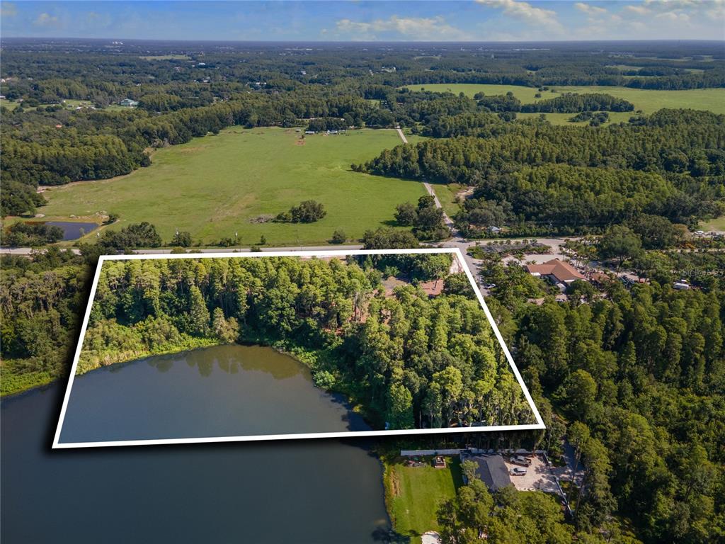 An aerial view of a large Mediterranean-style estate with a circular driveway, pool, and lake — 18150 BURRELL ROAD, ODESSA, FL