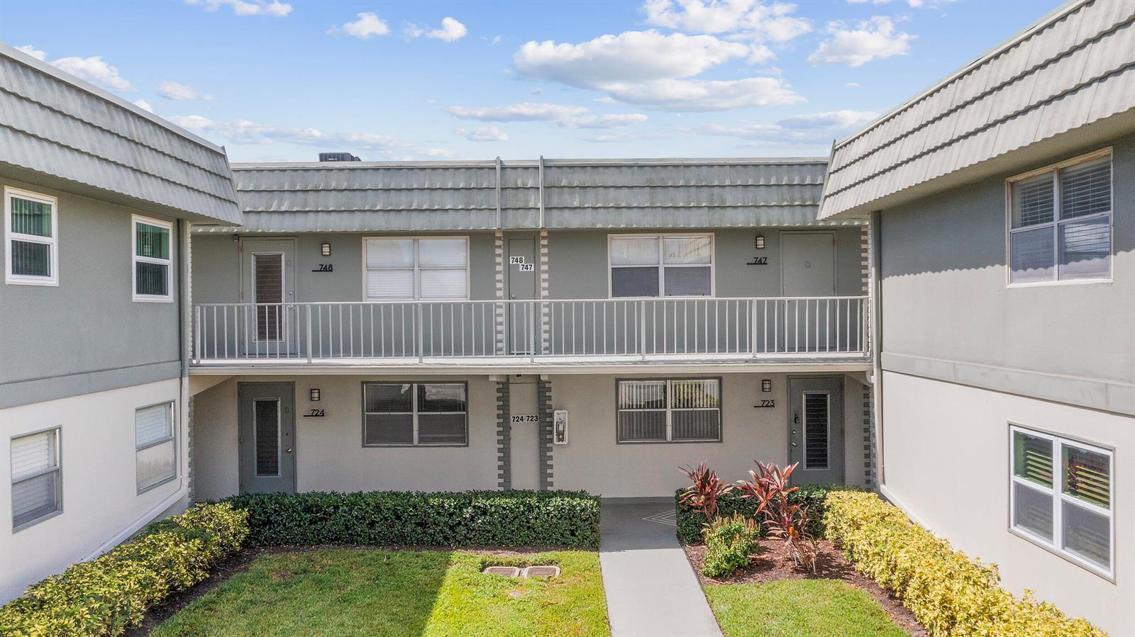 A two-story apartment building exterior features a balcony, green landscaping, and numbered unit doors — 723 Flanders P, Delray Beach FL 33484, DELRAY BEACH, FL