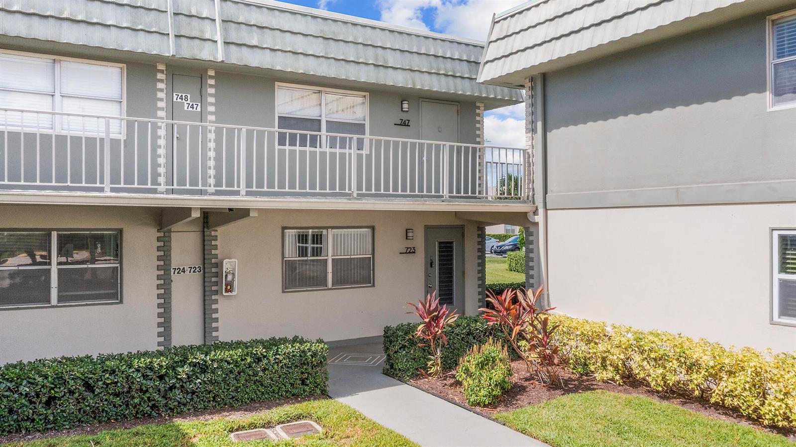 A two-story apartment building exterior features a balcony, walkways, and landscaped bushes — 723 Flanders P, Delray Beach FL 33484, DELRAY BEACH, FL
