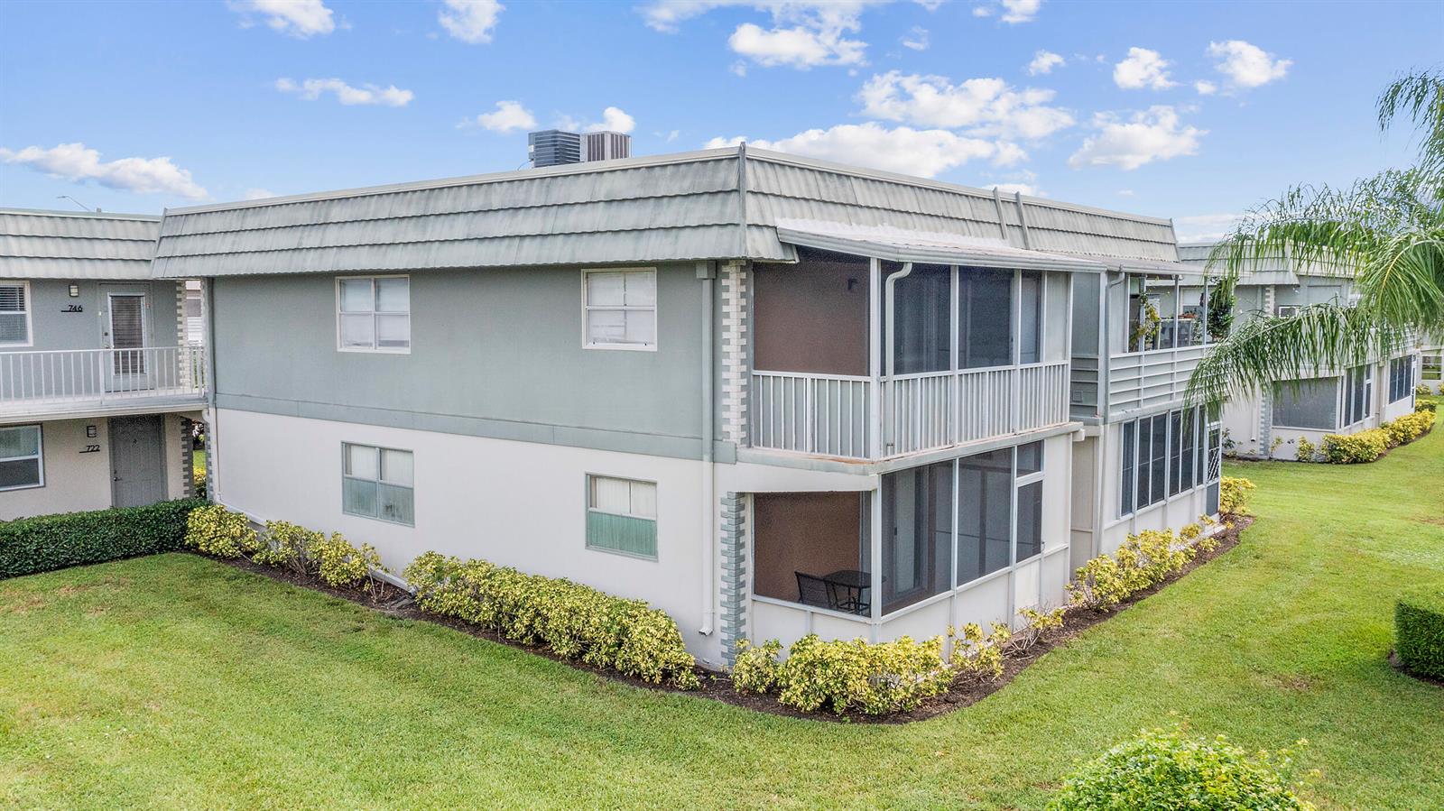 A two-story apartment building features light-colored stucco walls, screened balconies, and a flat roof — 723 Flanders P, Delray Beach FL 33484, DELRAY BEACH, FL