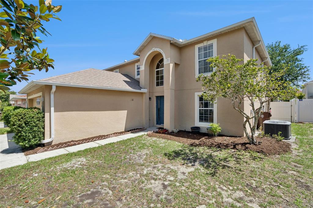 A two-story tan stucco house features a blue front door and a small front yard — 416 BARLYN AVENUE, HAINES CITY, FL