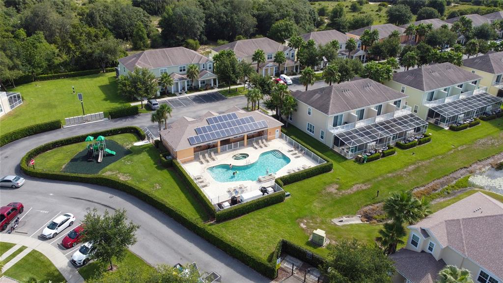 An aerial view shows a community swimming pool, playground, and surrounding residential townhomes — 17417 PLACIDITY AVENUE, CLERMONT, FL