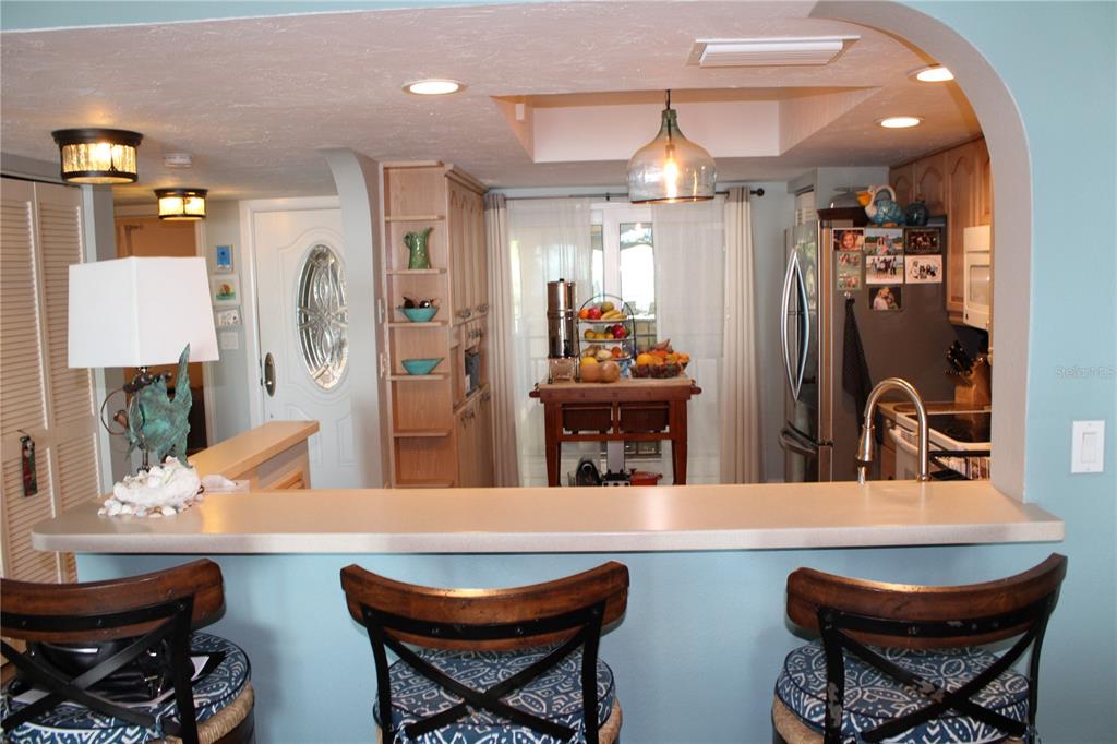 A kitchen with a breakfast bar, light wood cabinetry, and a central wooden island — 6470 MOURNING DOVE DRIVE UNIT 203, BRADENTON, FL