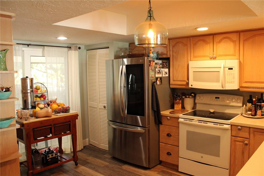 A kitchen features wood cabinets, stainless steel appliances, a white stove, and a rolling island — 6470 MOURNING DOVE DRIVE UNIT 203, BRADENTON, FL