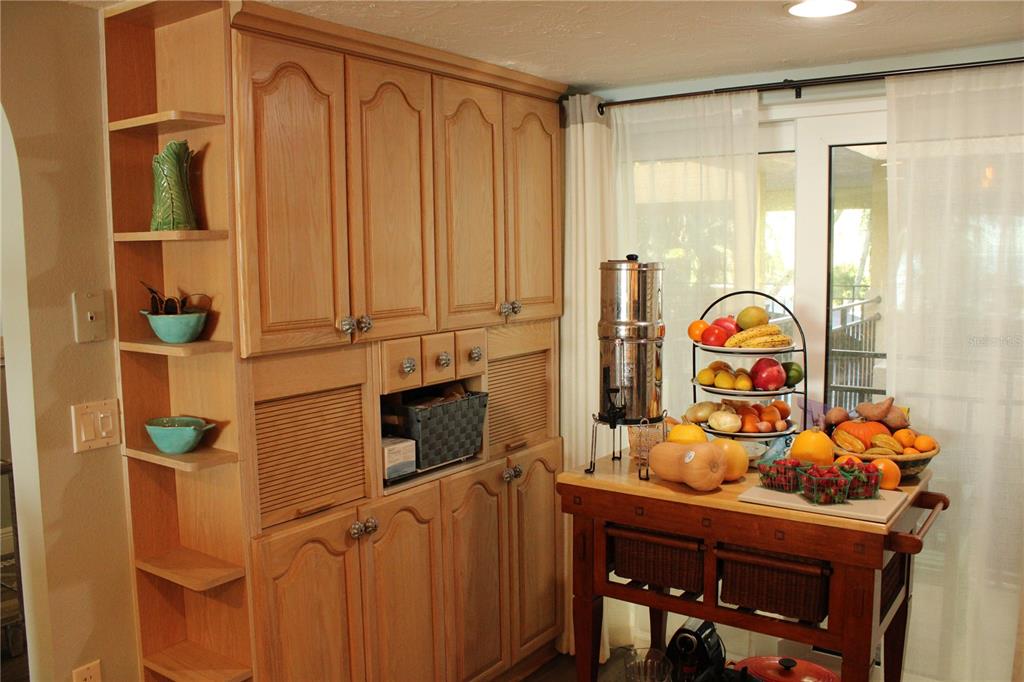 A kitchen features light wood cabinetry, open shelving, and a wooden island with fresh produce — 6470 MOURNING DOVE DRIVE UNIT 203, BRADENTON, FL
