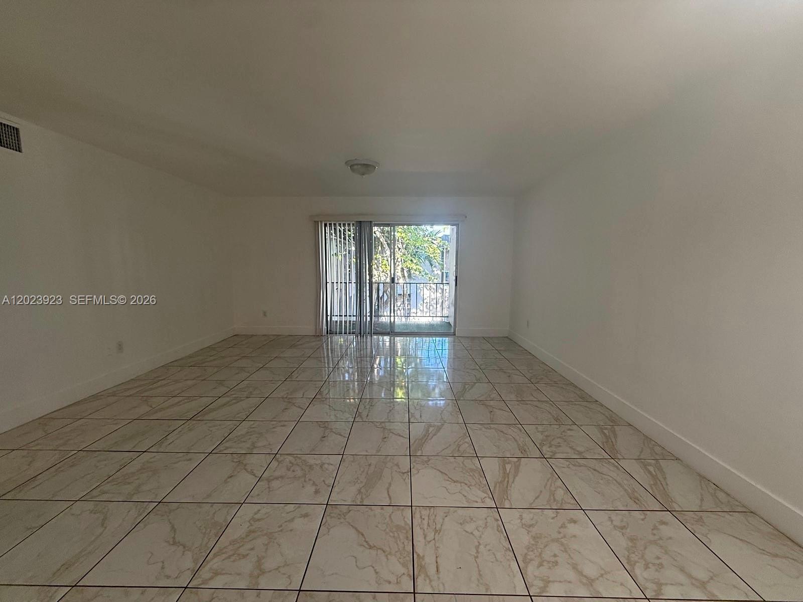 An empty room features white walls, a tiled floor, and a sliding glass balcony door — 10393 N Kendall Dr # U7, Miami FL 33176, MIAMI, FL