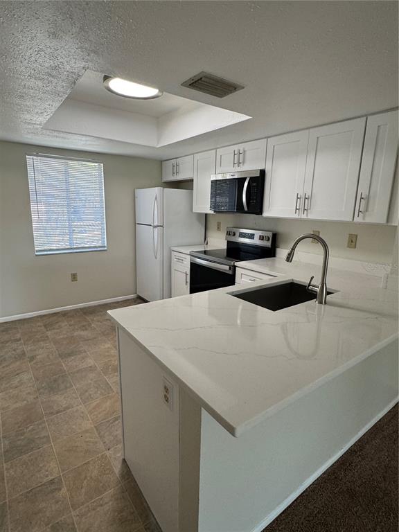 A kitchen features white cabinets, quartz countertops, stainless steel appliances, and a recessed ceiling light — 212 CYPRESS LANE, OLDSMAR, FL