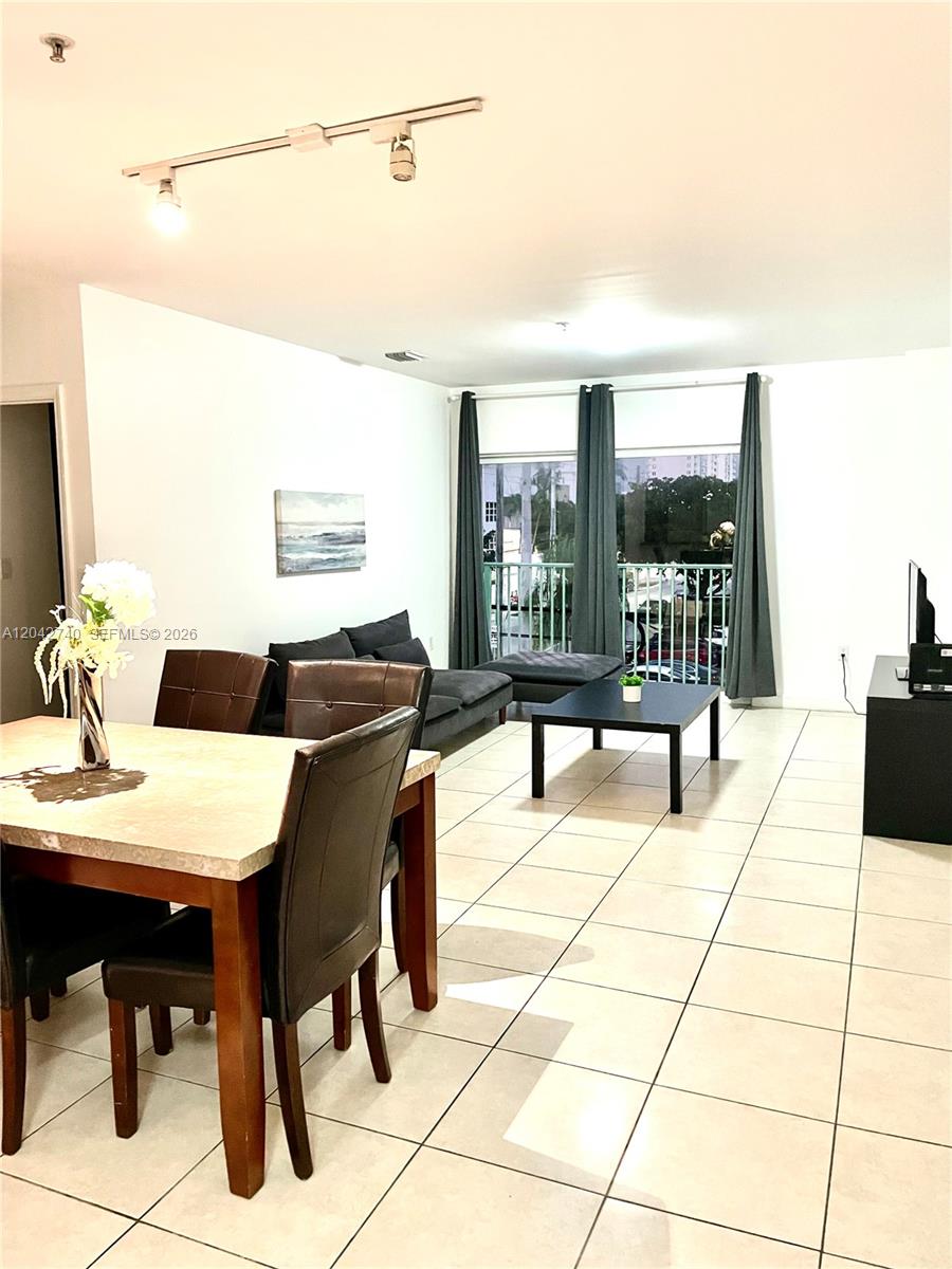 A dining area and living room with tile floors, track lighting, and a balcony view — 2280 SW 32nd Ave # 202, Miami FL 33145, MIAMI, FL