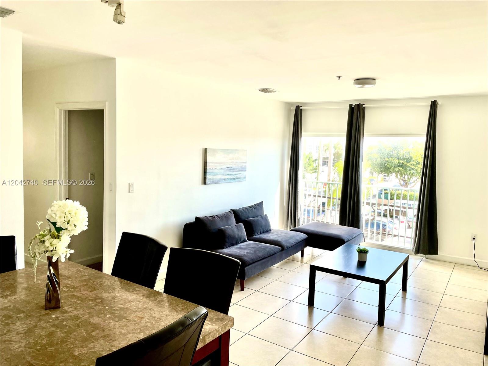 A living and dining area features tile floors, a dark sofa, and a balcony view — 2280 SW 32nd Ave # 202, Miami FL 33145, MIAMI, FL