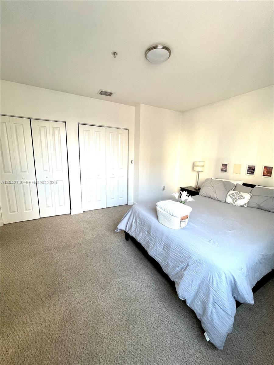A bedroom features a bed with grey bedding, carpeted flooring, and white closet doors — 2280 SW 32nd Ave # 202, Miami FL 33145, MIAMI, FL