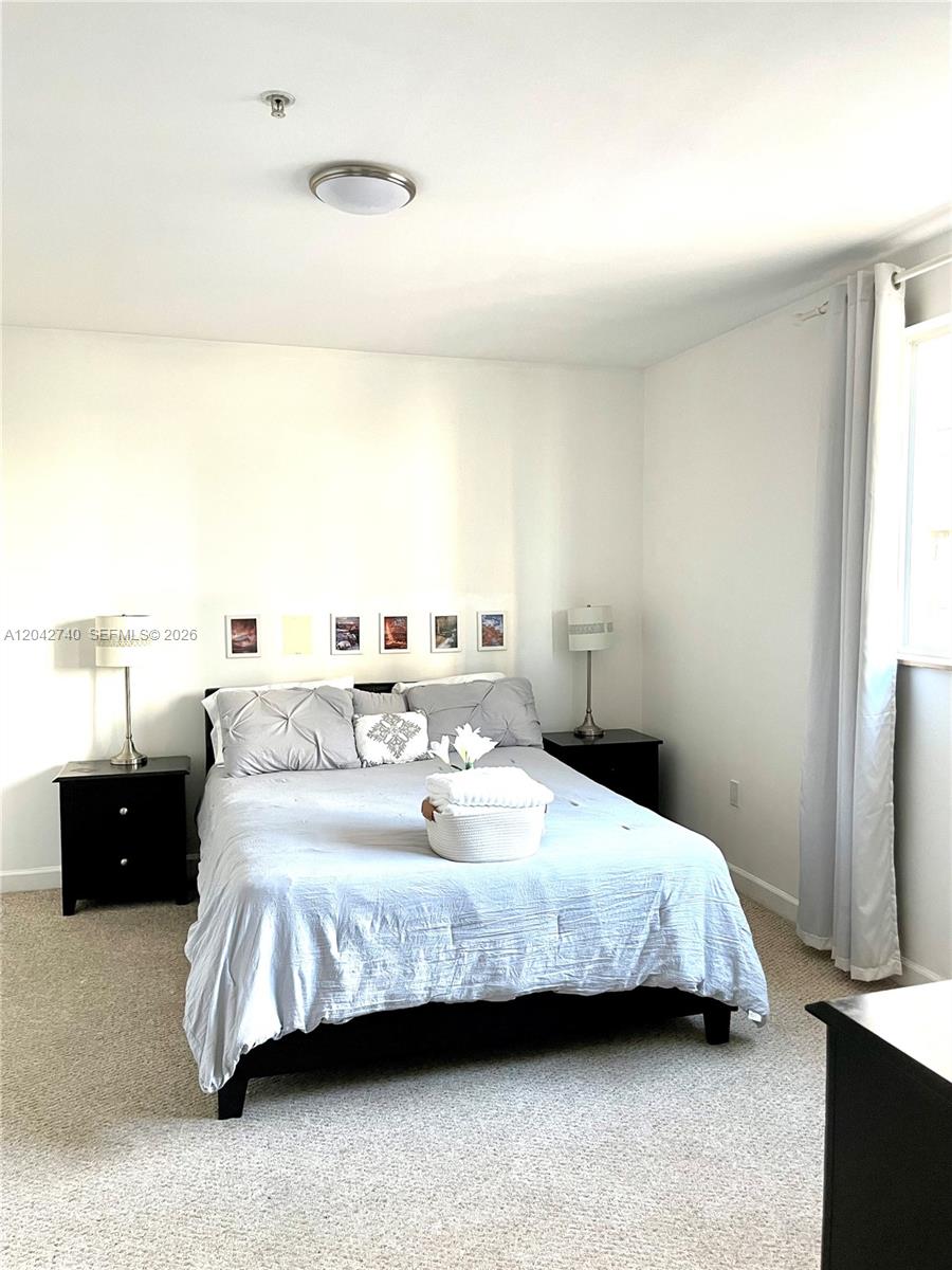 A bedroom features a bed with grey bedding, two black nightstands, and beige carpeting — 2280 SW 32nd Ave # 202, Miami FL 33145, MIAMI, FL