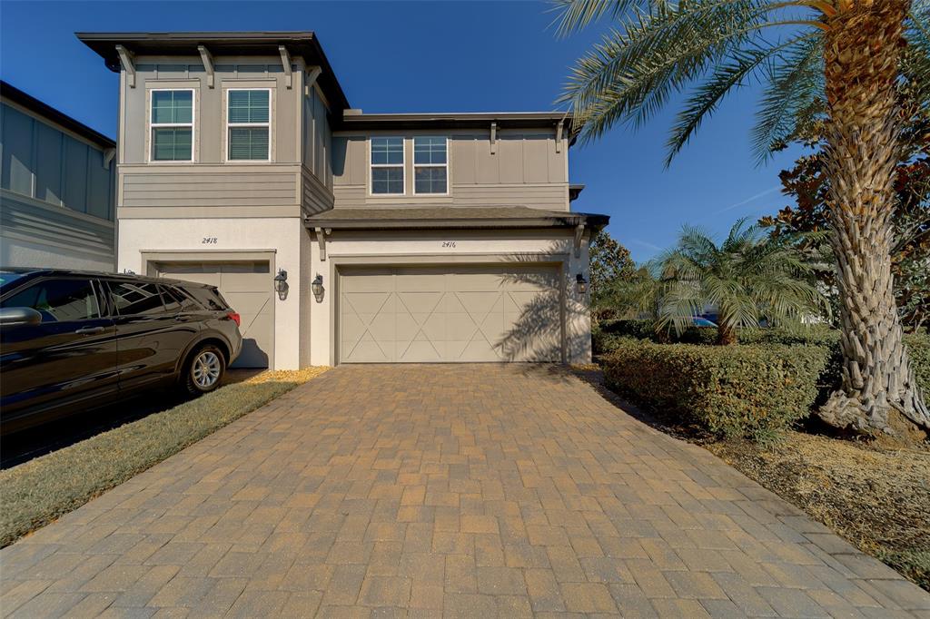A two-story house features a paved driveway, a two-car garage, and a palm tree — 2416 FOGGY CREEK CIRCLE, CLEARWATER, FL