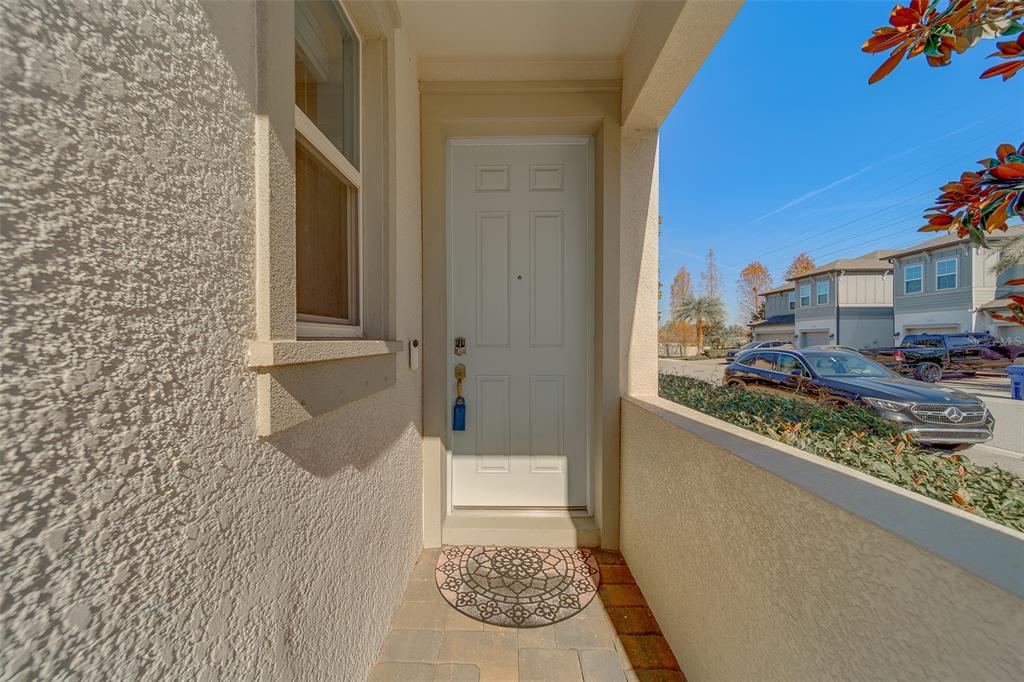 A white front door opens onto a small, covered porch with a patterned welcome mat — 2416 FOGGY CREEK CIRCLE, CLEARWATER, FL