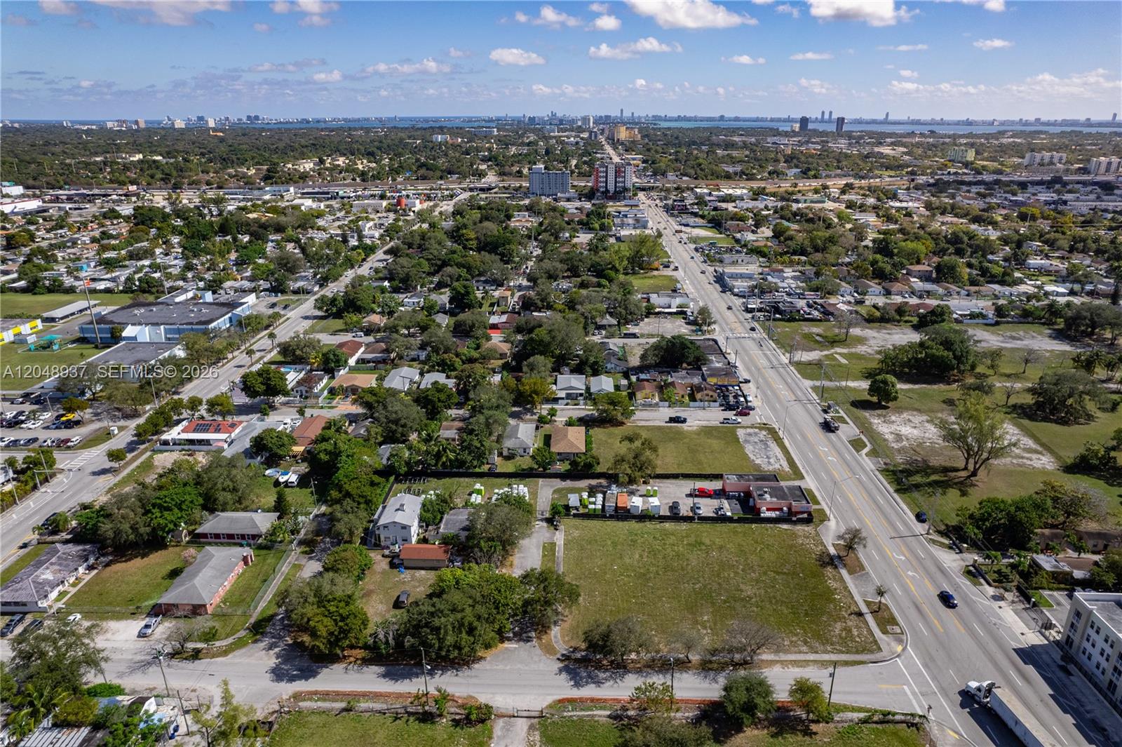 An aerial view shows a vacant lot and surrounding residential and commercial buildings in a city — 1113 NW 79th St, Miami FL 33150, MIAMI, FL