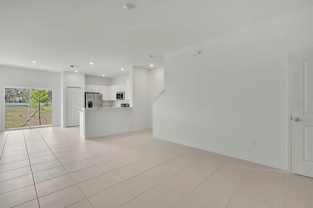 An open-concept living area features white walls, tile flooring, and a kitchen with white cabinetry — 36144 RISA MICHELE STREET, ZEPHYRHILLS, FL