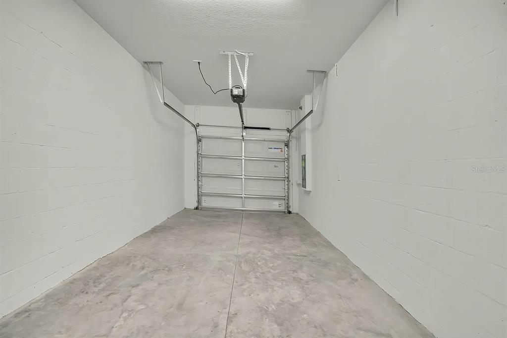 An empty garage features white concrete block walls, a concrete floor, and a sectional door — 36144 RISA MICHELE STREET, ZEPHYRHILLS, FL