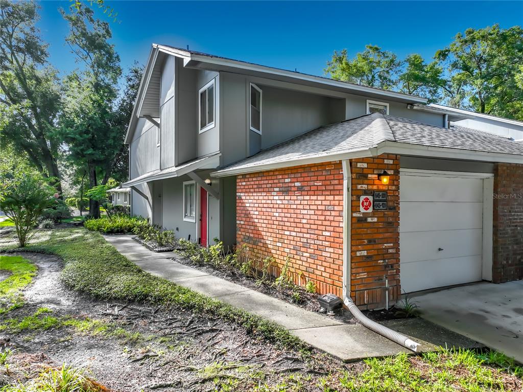 A two-story building with gray siding, a brick facade, and a white garage door — 645 LAUREL OAK LANE UNIT 201, ALTAMONTE SPRINGS, FL