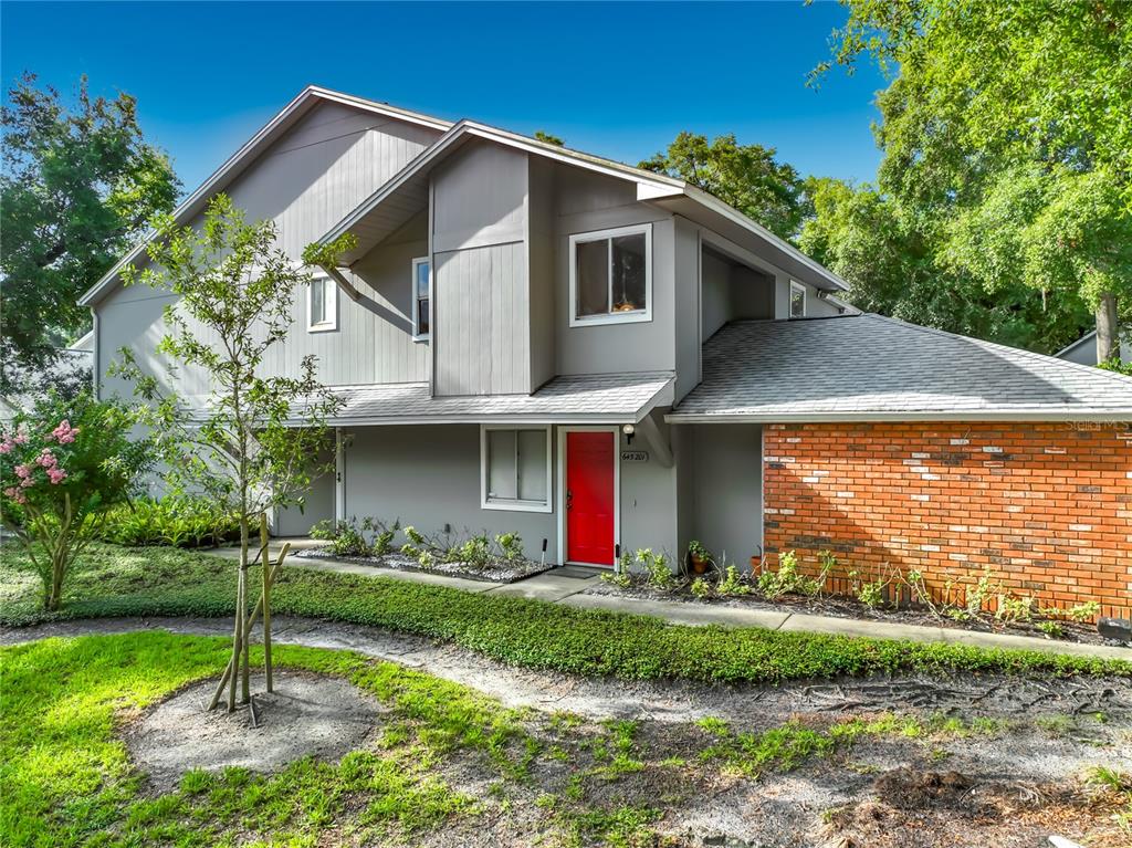A two-story gray townhouse features a red front door and a brick accent wall — 645 LAUREL OAK LANE UNIT 201, ALTAMONTE SPRINGS, FL