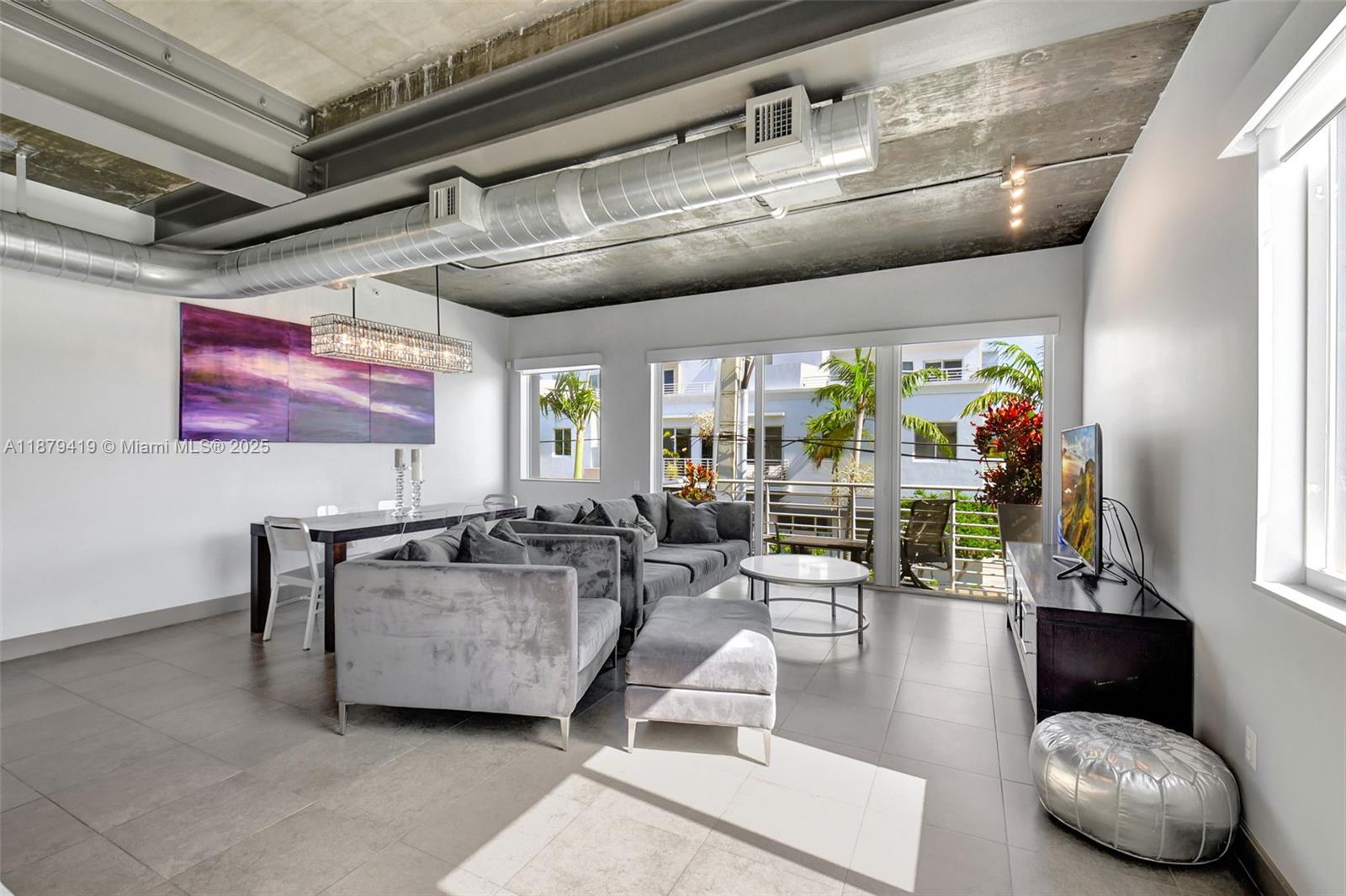 A living and dining room features an industrial concrete ceiling, exposed ductwork, and large windows — 110 SE 2nd ST # 203, Delray Beach FL 33444, DELRAY BEACH, FL