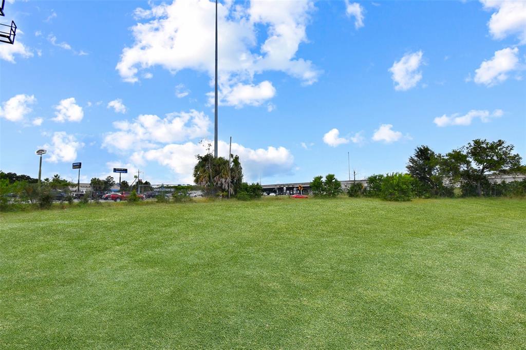 A wide, grassy field sits in front of a highway overpass under a blue sky — 7268 MORSE AVENUE, JACKSONVILLE, FL