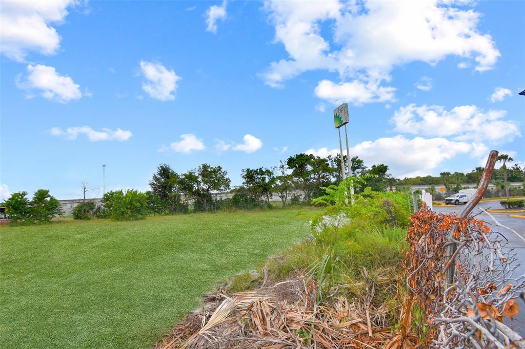 A grassy vacant lot features a tall BP gas station sign and a chain-link fence — 7268 MORSE AVENUE, JACKSONVILLE, FL