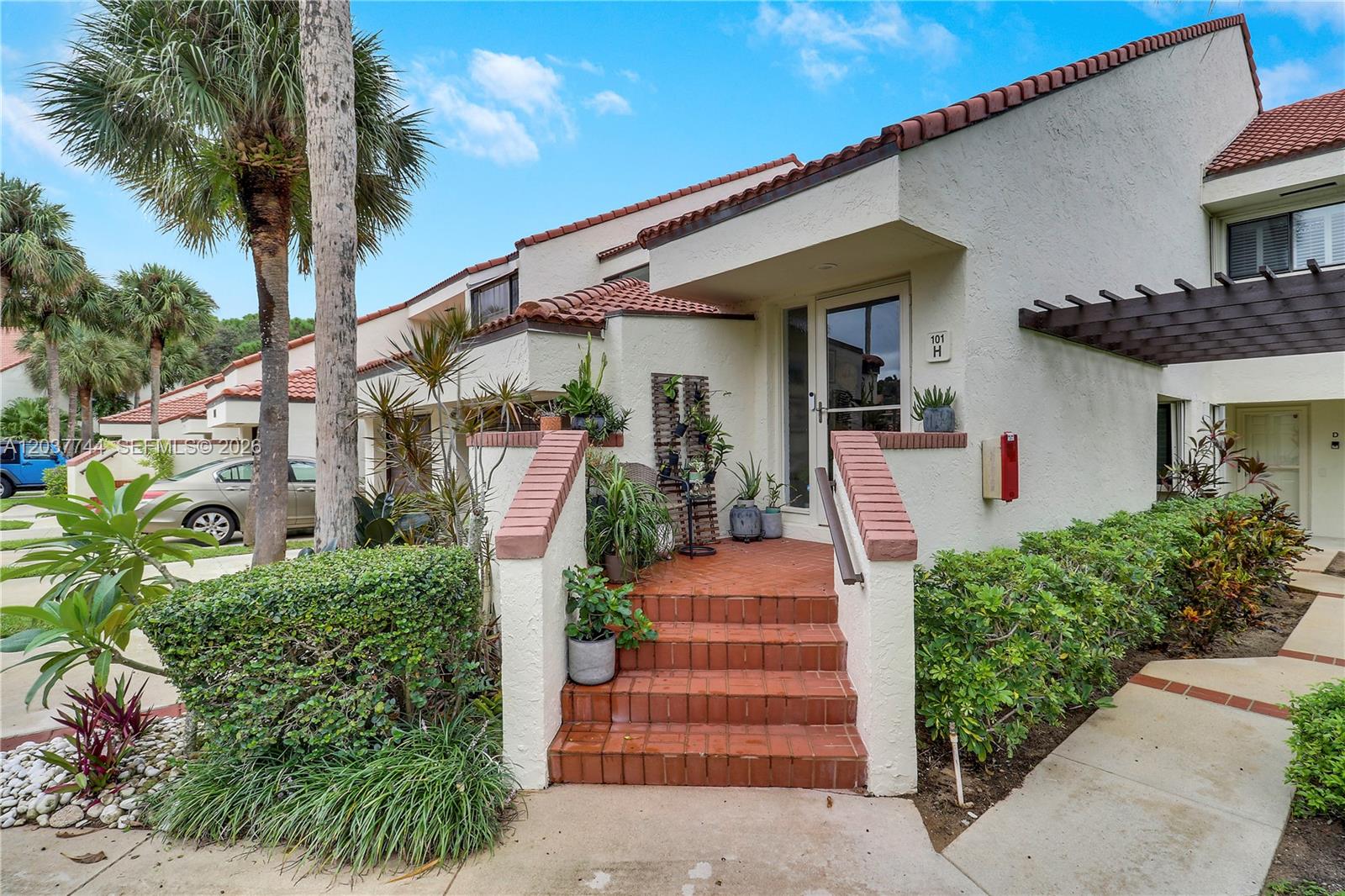 The exterior of a multi-unit residential building features a brick staircase leading to a front entrance — 101 Sea Oats Dr # H, Juno Beach FL 33408, JUNO BEACH, FL