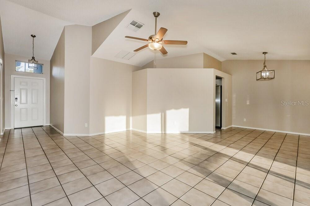 An open-concept living area features light-colored tile flooring, vaulted ceilings, and a ceiling fan — 227 BELFORT PLACE, VALRICO, FL