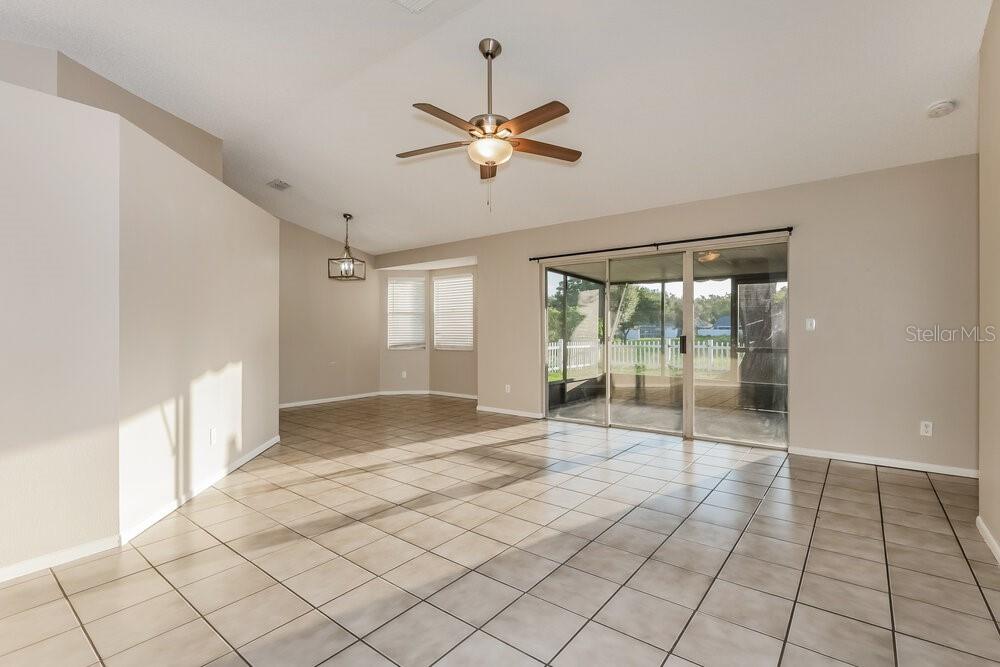 An open-concept living area features light-colored tile flooring, a ceiling fan, and sliding glass doors — 227 BELFORT PLACE, VALRICO, FL