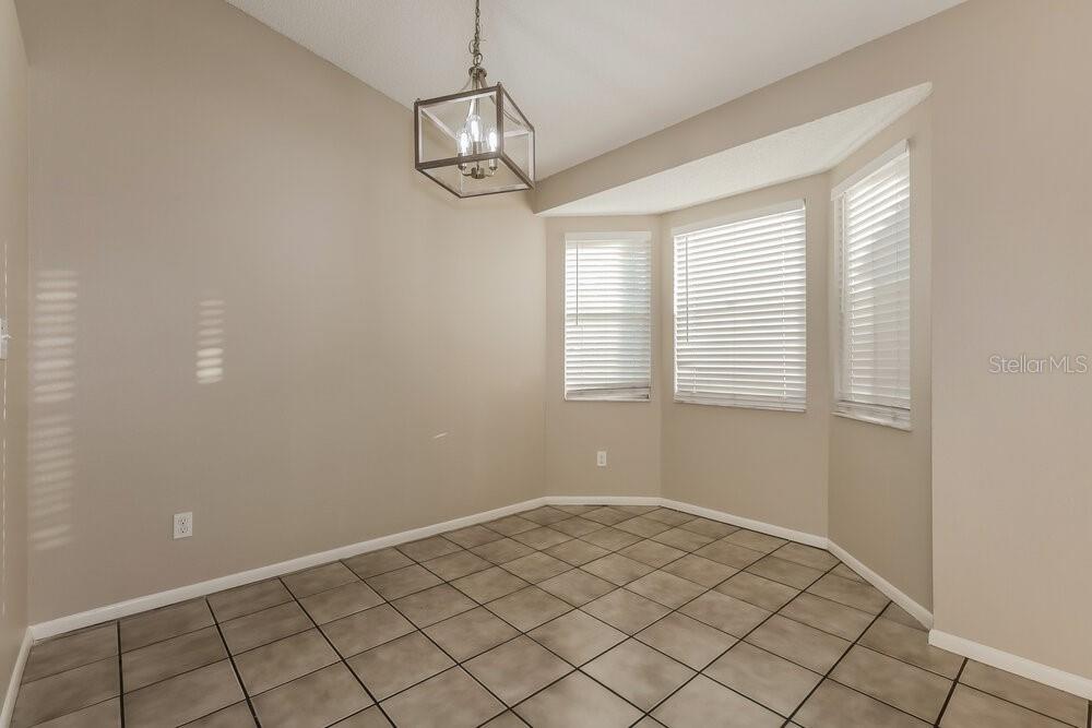 A dining area with tile flooring, a hanging light fixture, and a bay window — 227 BELFORT PLACE, VALRICO, FL