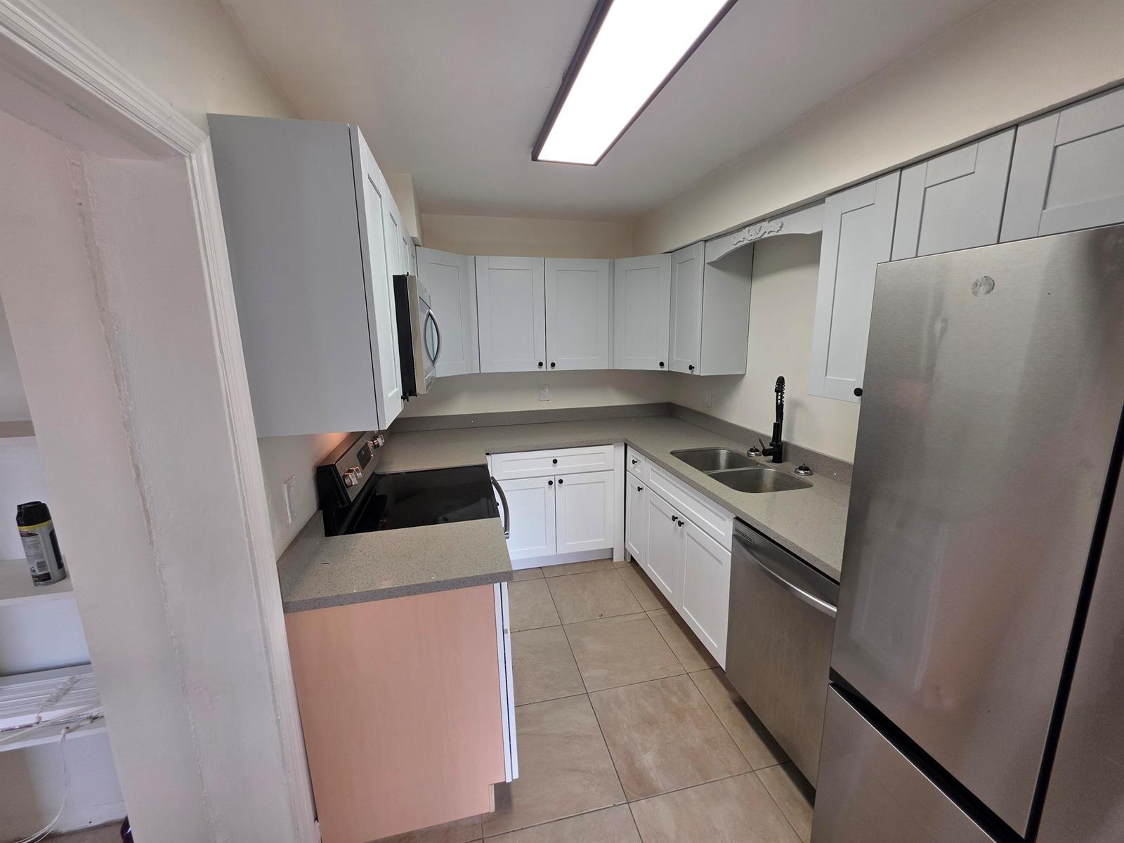 A kitchen features white cabinets, gray countertops, stainless steel appliances, and light-colored tile flooring — 15427 San Diego Drive, FL 33470, FL