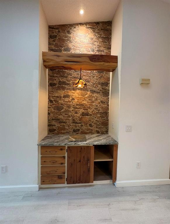 A built-in wet bar features a stone-tiled wall, live-edge wood shelf, and granite countertop — 39650 US HIGHWAY 19 N UNIT 441, TARPON SPRINGS, FL