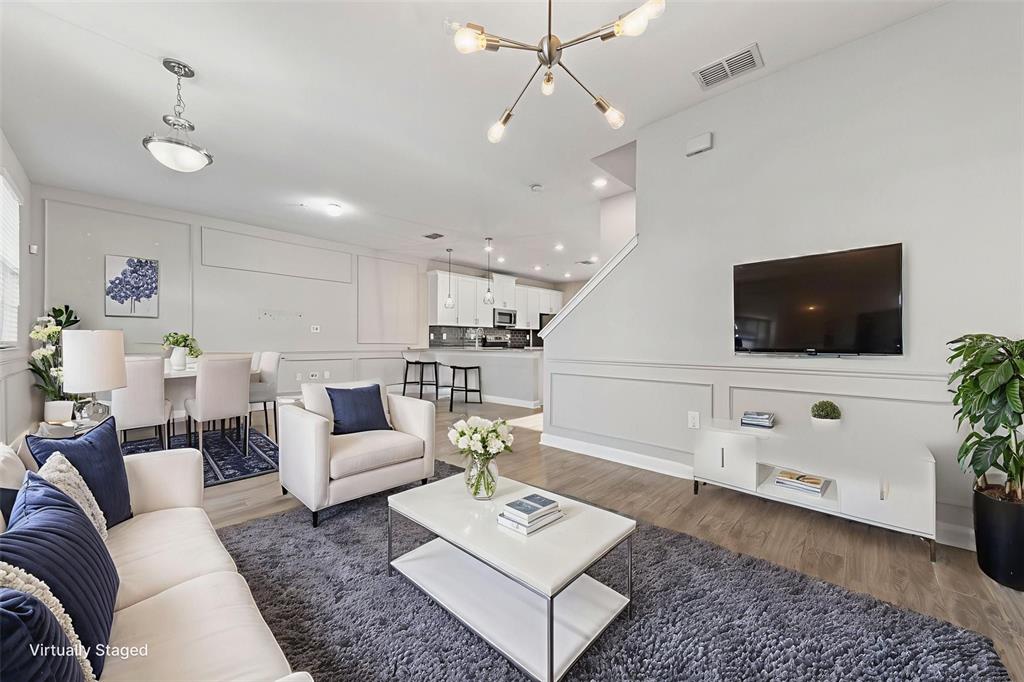 A living room with a gray rug, white sofa, armchair, and an open kitchen beyond — 11626 EPIC AVENUE, ORLANDO, FL