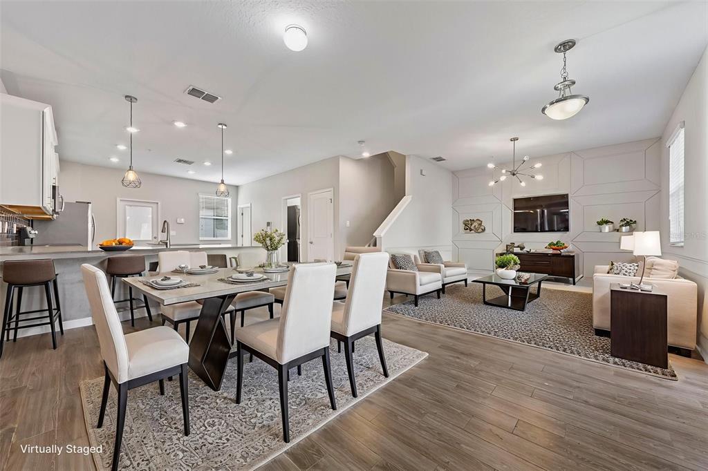 An open-concept living and dining area with light wood floors and modern light fixtures — 11626 EPIC AVENUE, ORLANDO, FL
