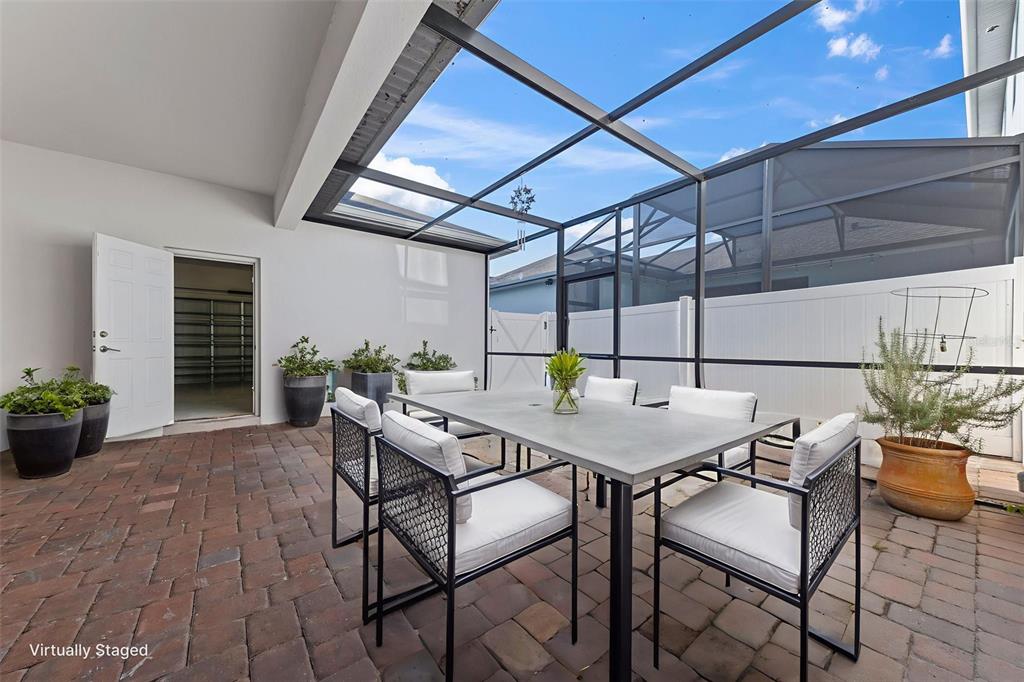 A patio with a brick floor, dining set, and screened-in roof enclosure — 11626 EPIC AVENUE, ORLANDO, FL